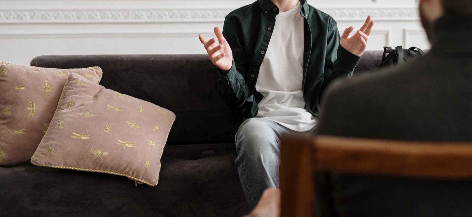 Client sitting on a couch talking to a therapist sitting in a chair.